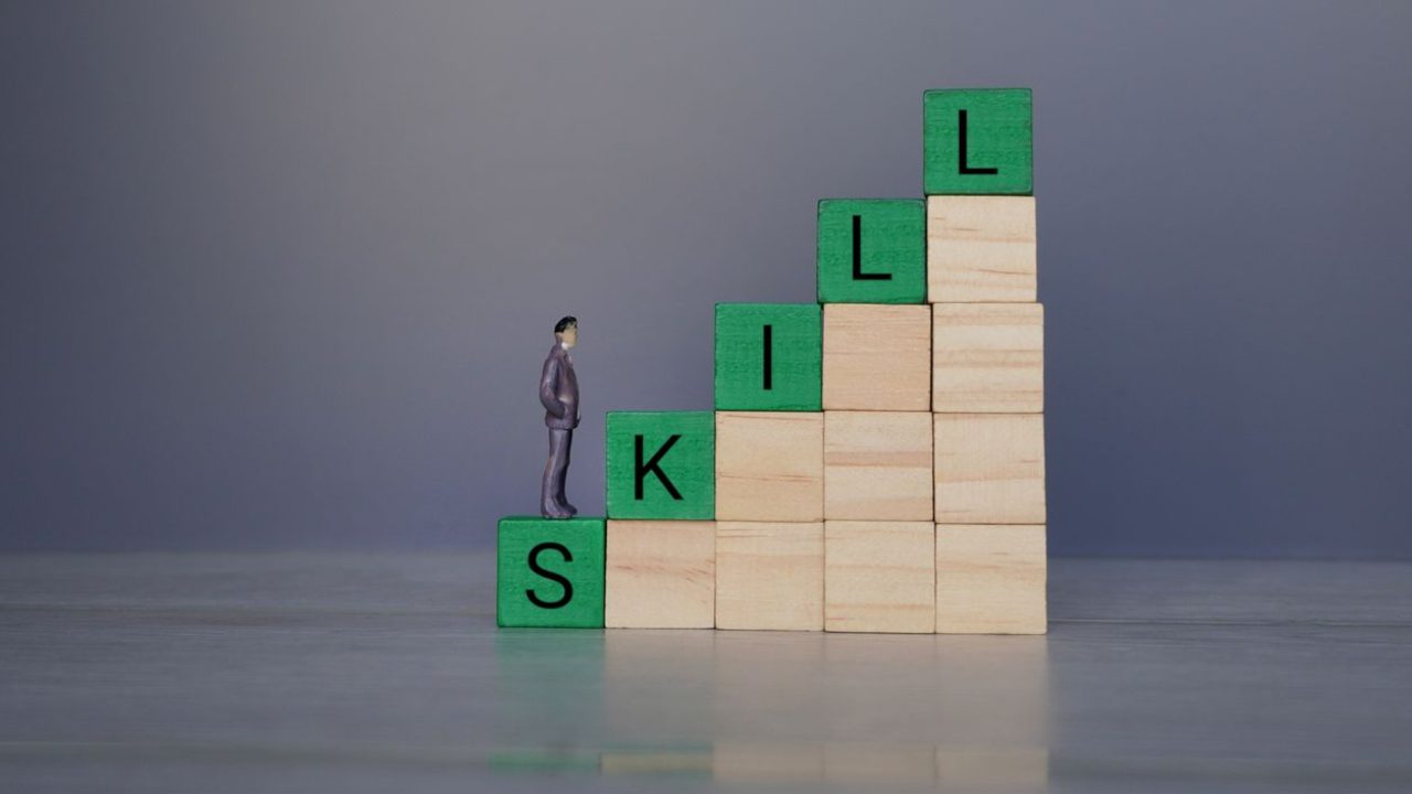 a man standing on a stack of wooden blocks with the word skills